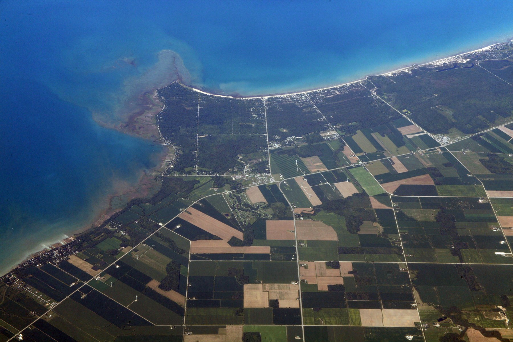 Aerial photograph of Kettle Point projecting into Lake Huron, with shoreline settlement, woods and surrounding fields.