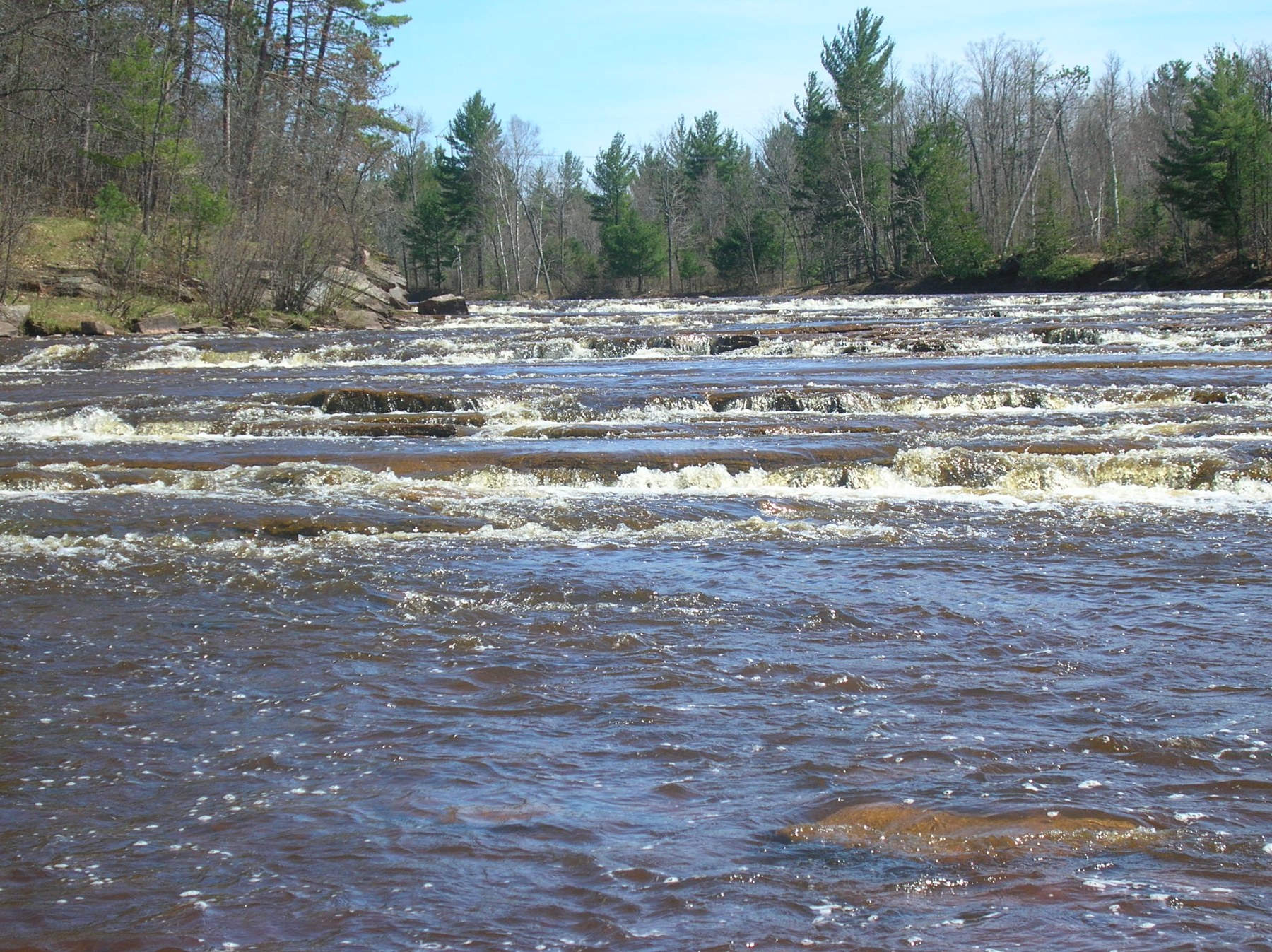 Rocky rapids and wooded banks at the lower falls of the Bad River, photographed by USFWS in 2010.