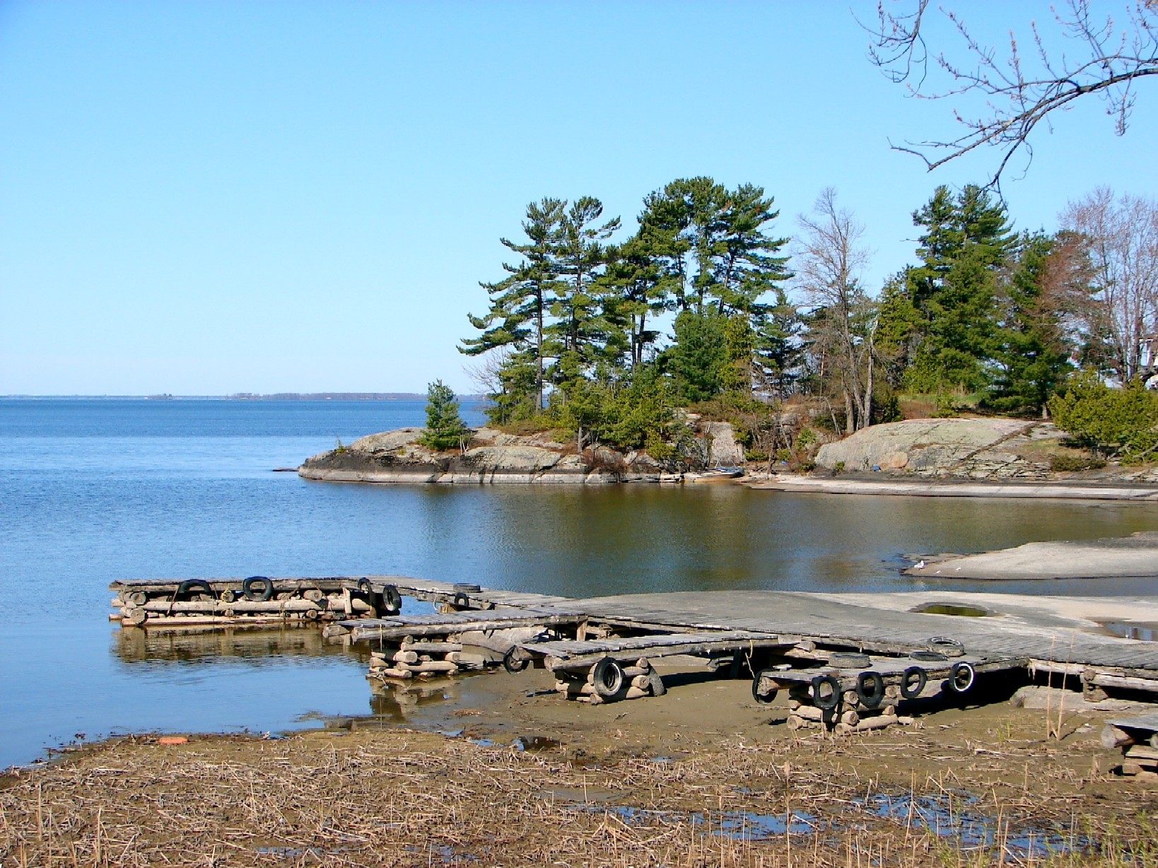 Shoreline at Garden Village with Lake Nipissing, trees, rock and wooden docks.