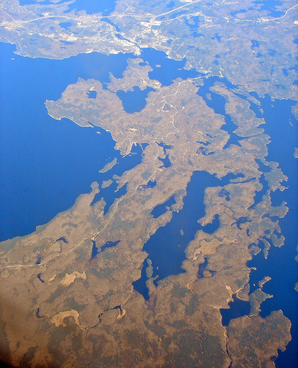 Aerial view of Parry Island with forests, roads, small lakes and the surrounding blue water of Georgian Bay.