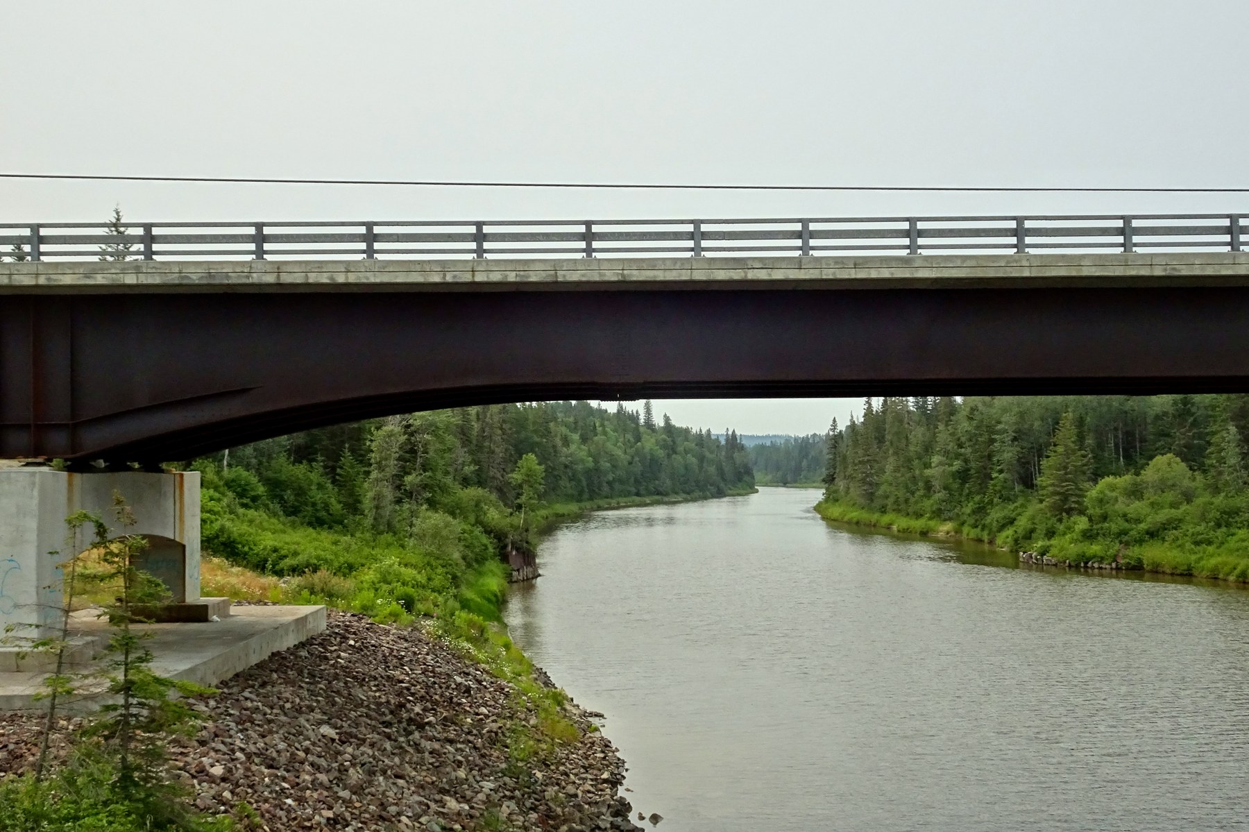 The Pic River passes under the Highway17 bridge between green forested banks.