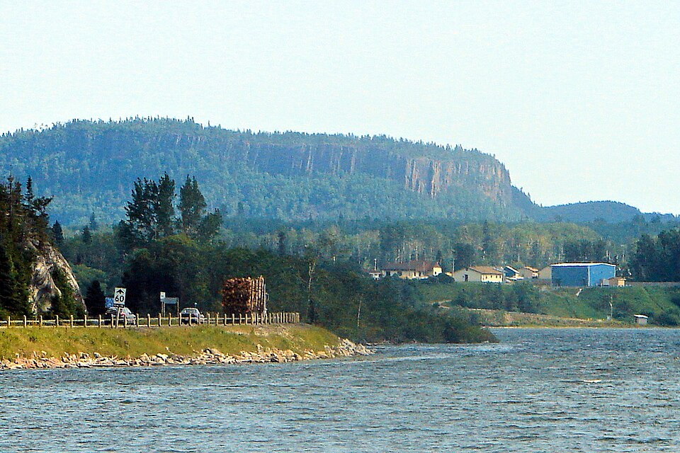 Lake Helen with houses and a road on the opposite shore beneath a rocky wooded ridge.