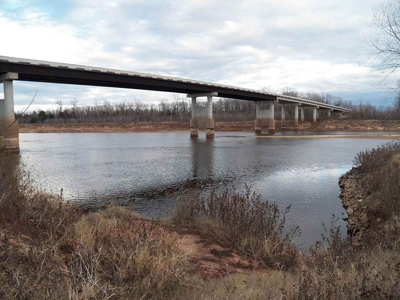 The Red River near Lewisville in southwestern Arkansas, with a modern highway bridge, winter vegetation and exposed riverbank.