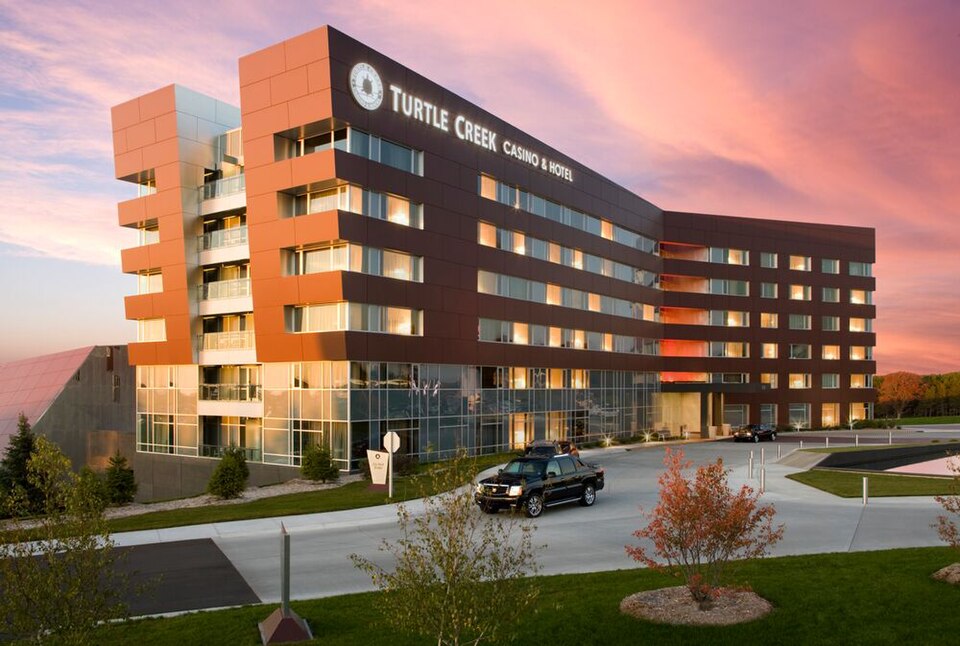 The multi-story Turtle Creek Casino and Hotel exterior in orange and dark tones beside parked cars.