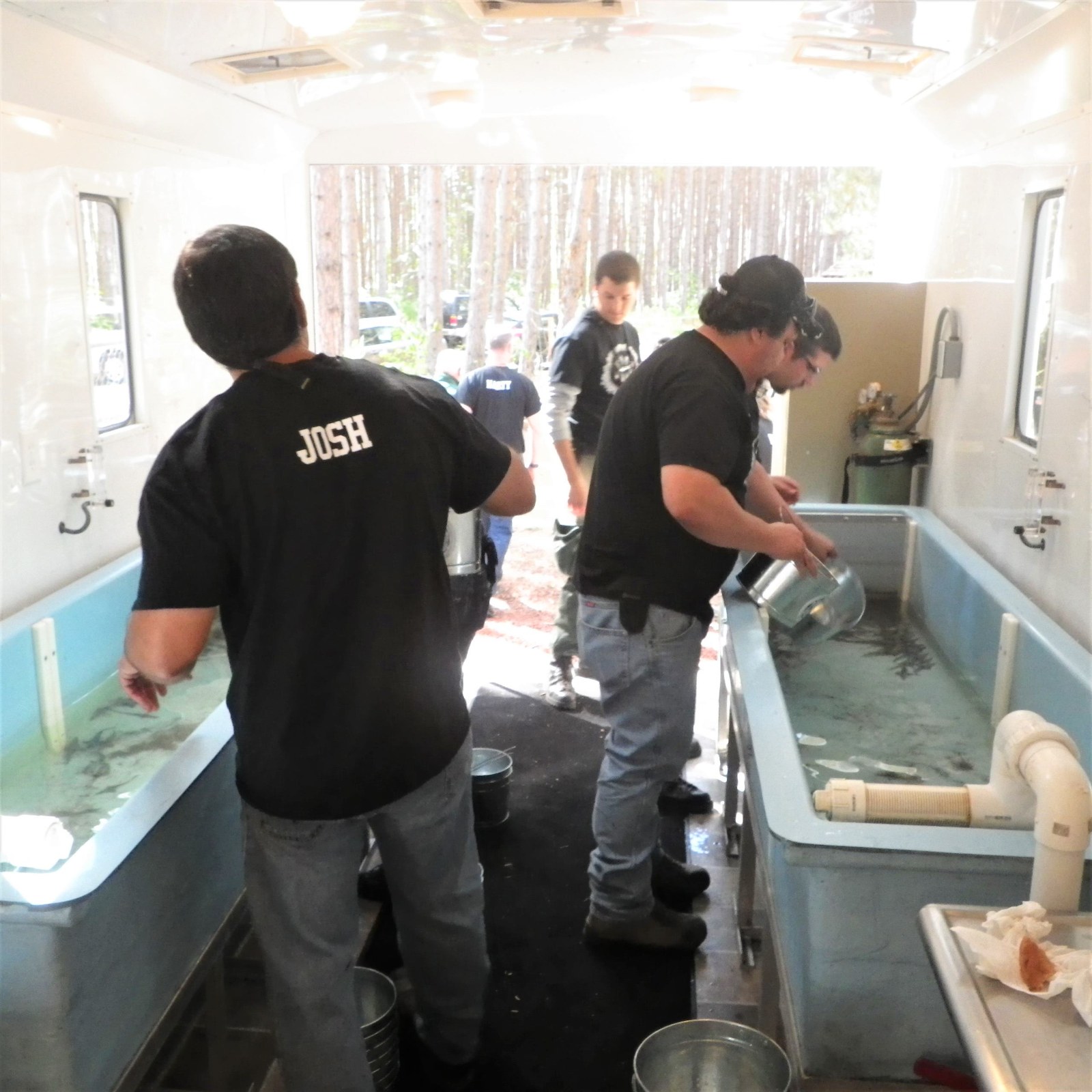 People work beside rectangular tanks of water inside a fish-rearing unit.