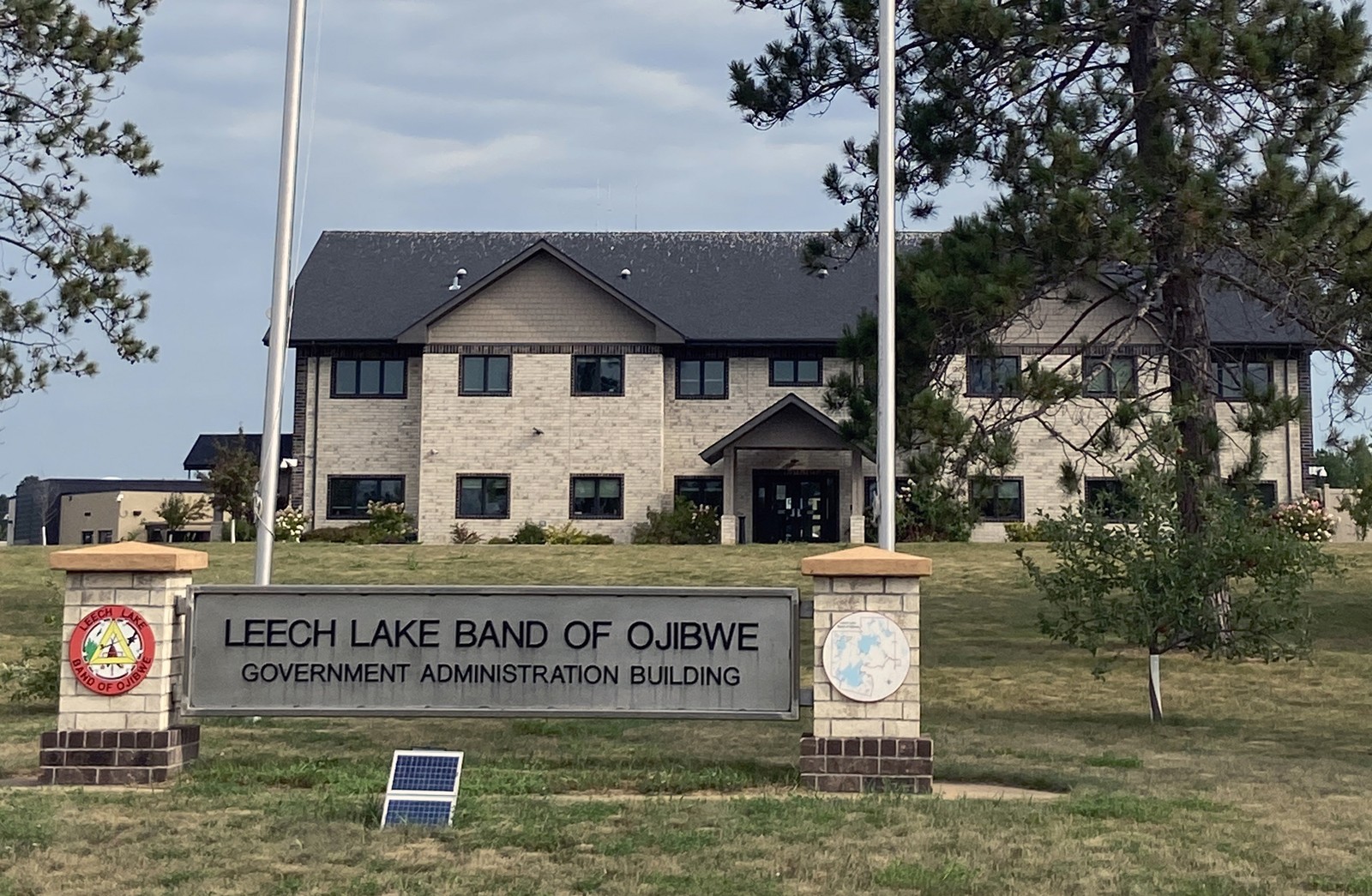 Leech Lake Band of Ojibwe Government Administration Building in Cass Lake, with the full identifying entrance sign, lawn and trees.
