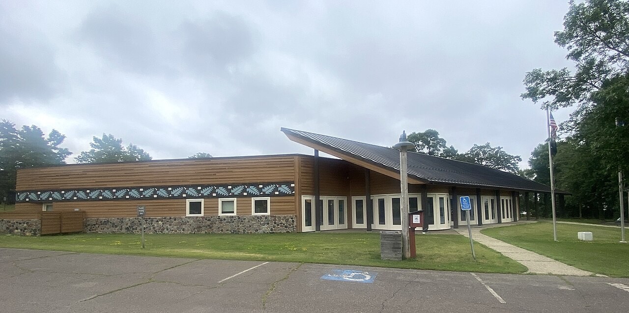Full exterior view of the Mille Lacs Indian Museum, including cedar siding, roof, windows, parking area and entrance path.