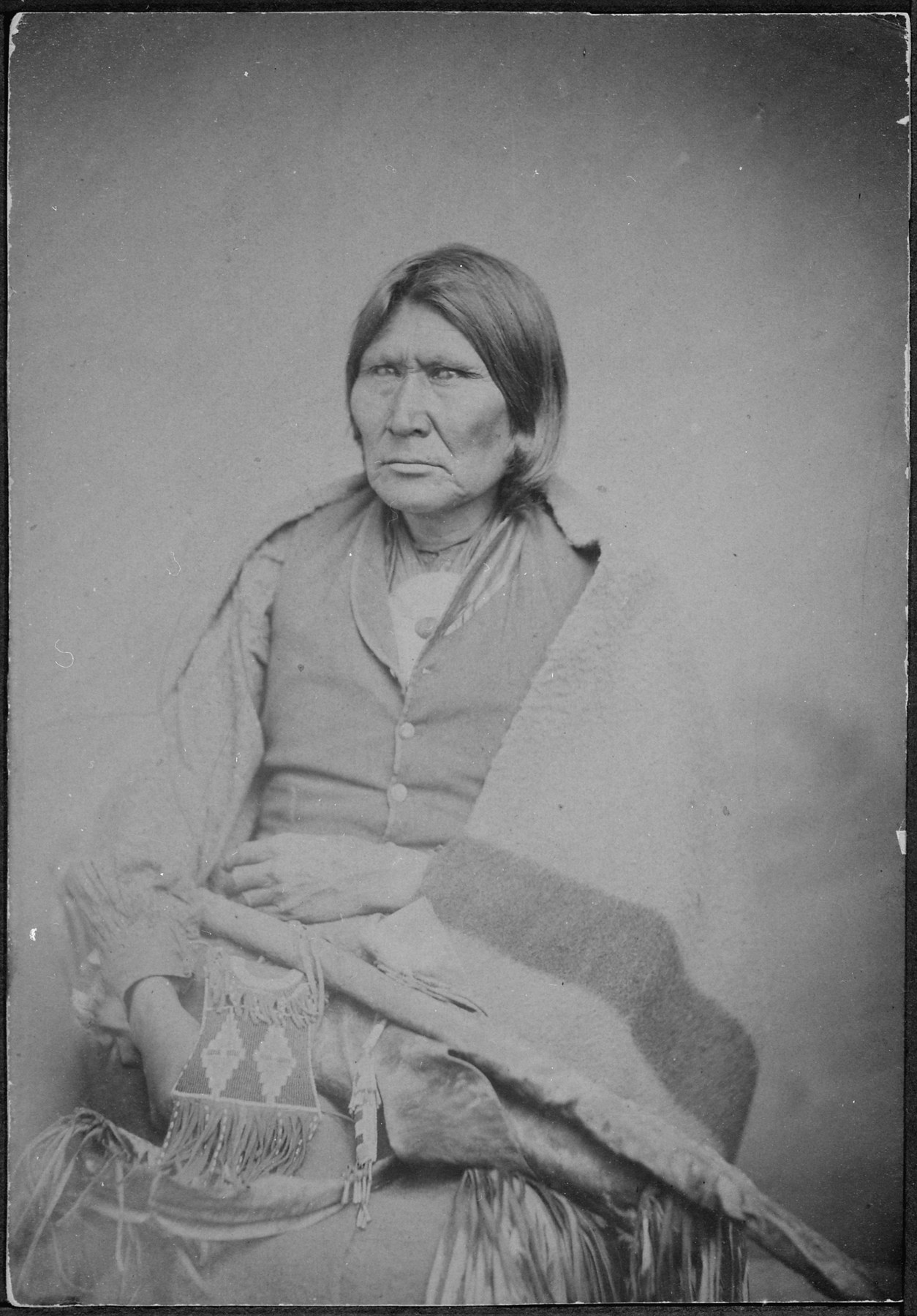 One man sits wrapped in a blanket in an archival portrait; the NARA record is titled for Horseback, a Nakoney chief, and his bodyguard, without resolving the frame's sitter here.