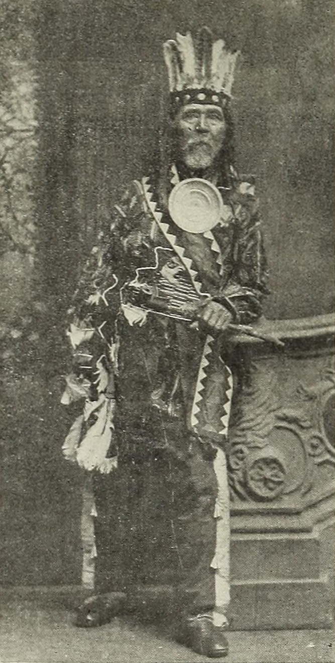 Historical full-length portrait of Andrew J. Blackbird standing beside a carved pedestal.