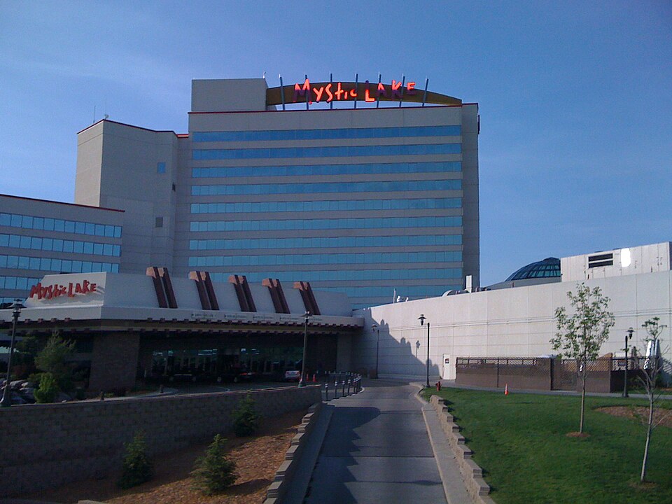 Mystic Lake’s hotel and casino exterior beneath a blue sky, with the entrance driveway in the foreground.